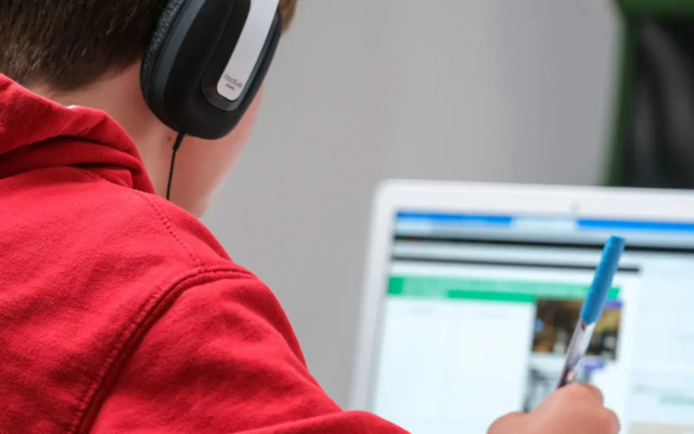 Collégien qui fait ses devoirs sur son ordinateur