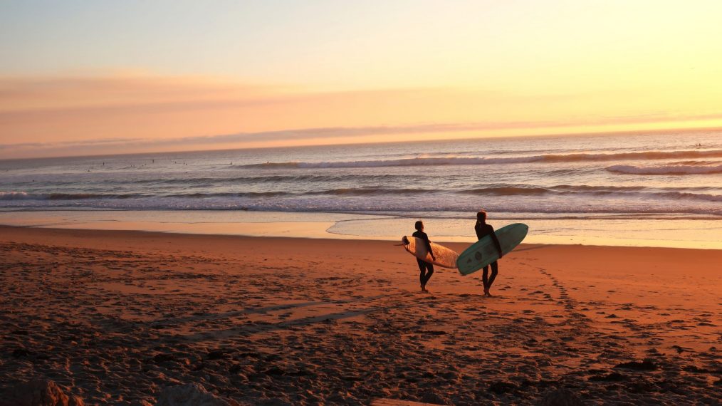 Plage avec surfeurs, au coucher de soleil