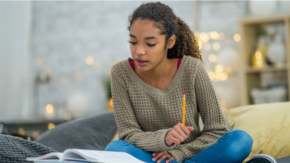 étudiante assise en tailleur en train de faire ses devoirs